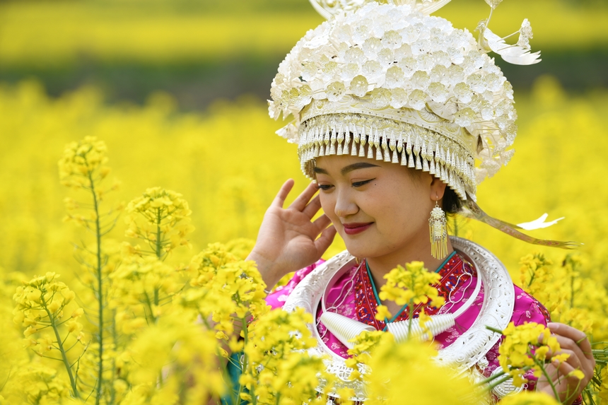 身著民族服裝與油菜花合影。