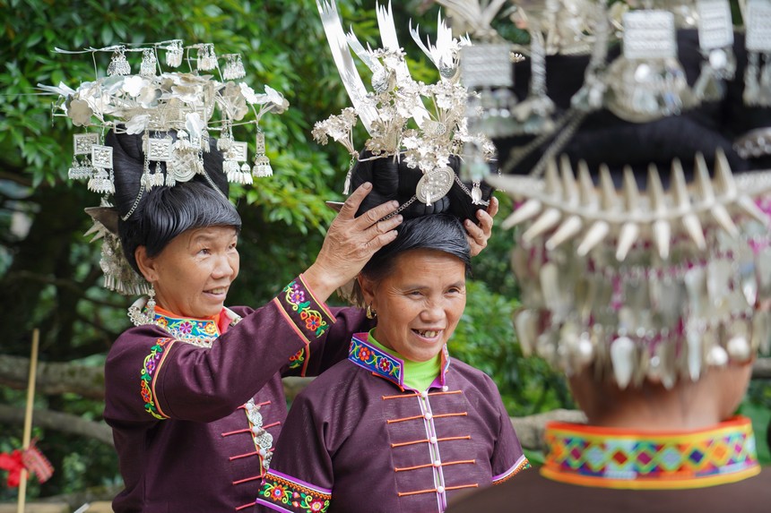 7月10日，貴州省丹寨縣排調(diào)鎮(zhèn)羊告村，李金英（左一）幫助苗族婦女戴銀飾。